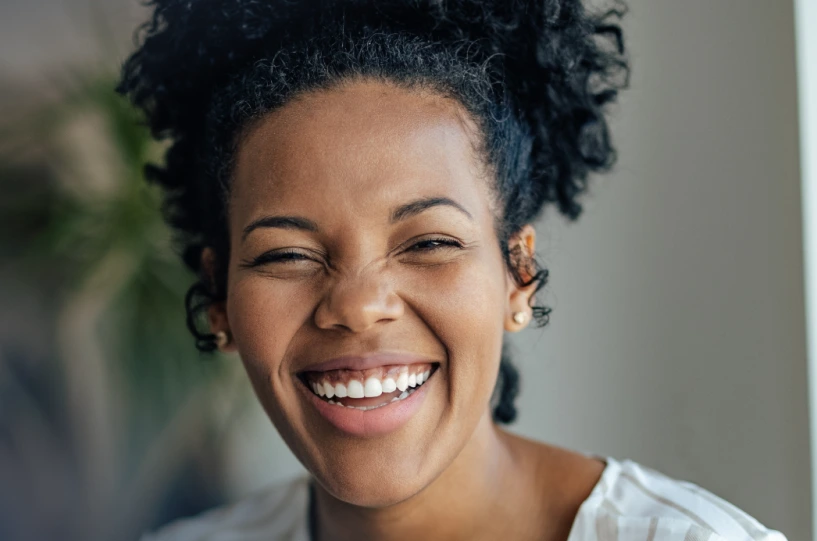 Smiling woman in light-colored shirt with Progressive Movement Inc. logo and text about psychiatric care and personalized medication management